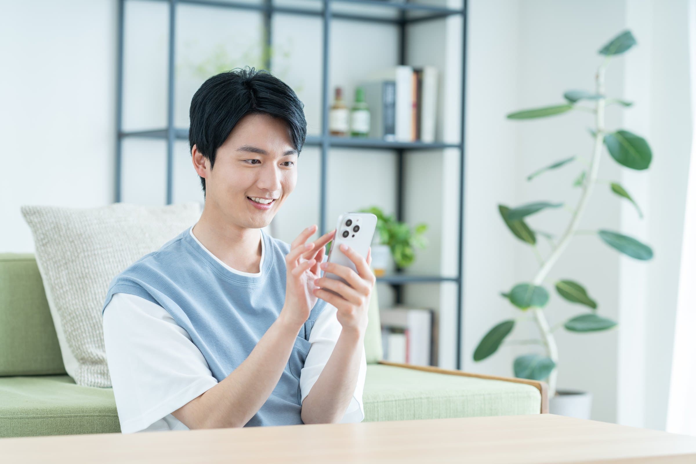 自宅でスマートフォンを操作する男性